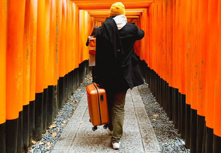 Probeetle - człowiek z walizką idzie przez "tunel" pomarańczowych pali